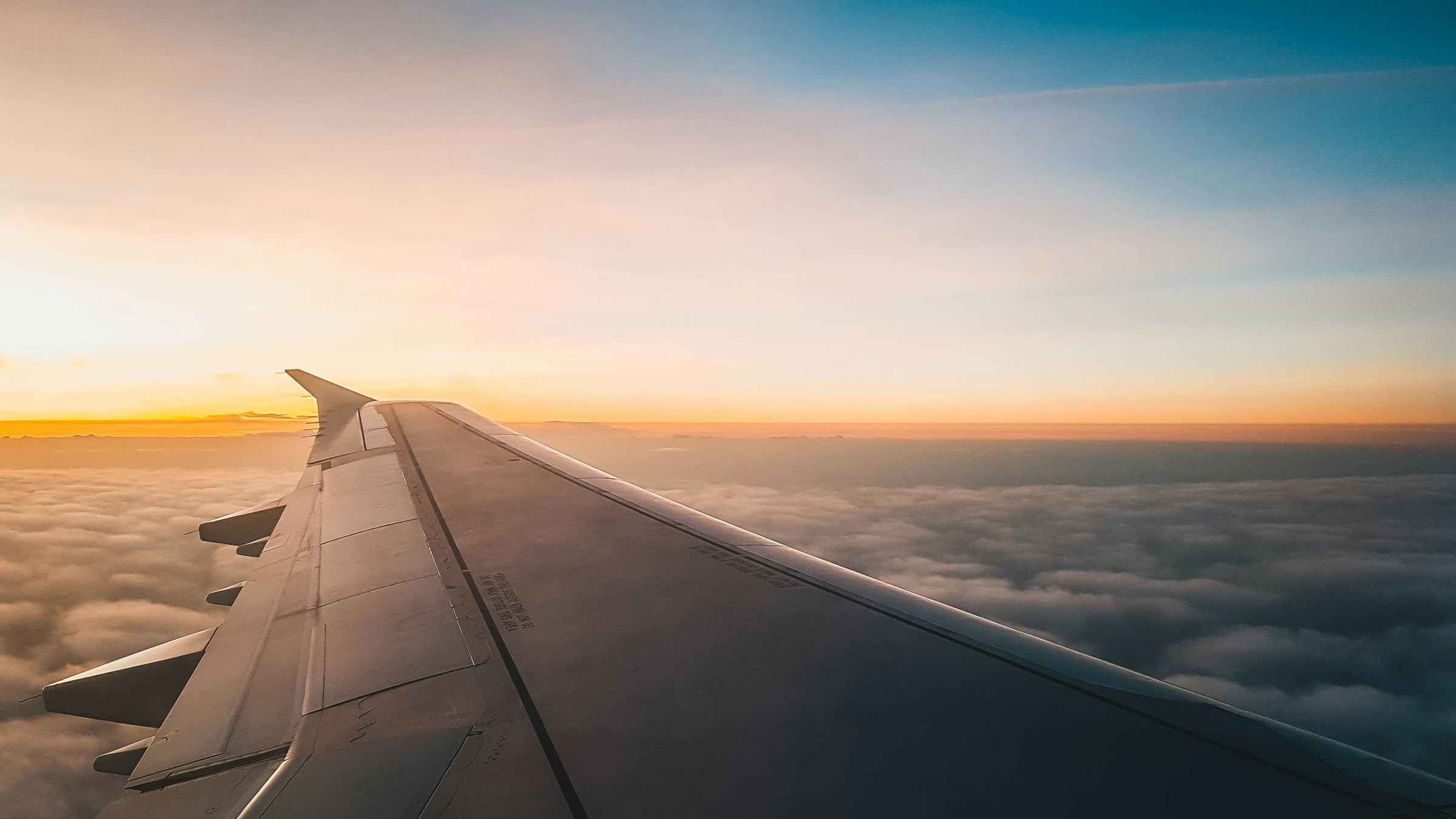 Aircraft wing above clouds at sunrise